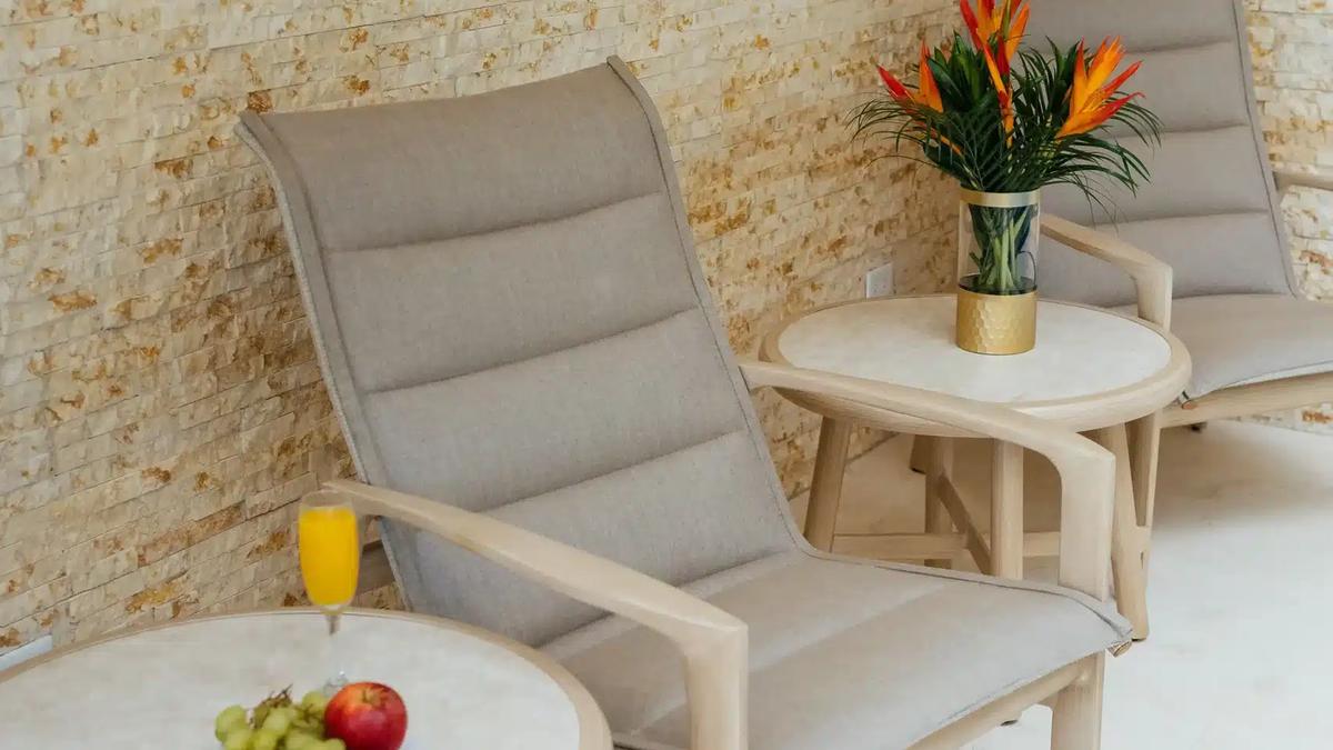 Patio lounge chairs at Casa Rambutan against a stone wall with fruit and mimosas