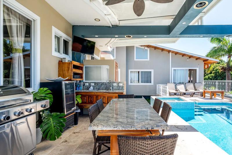 Covered outdoor kitchen and granite dining table beside the pool at Casa Alta Vista