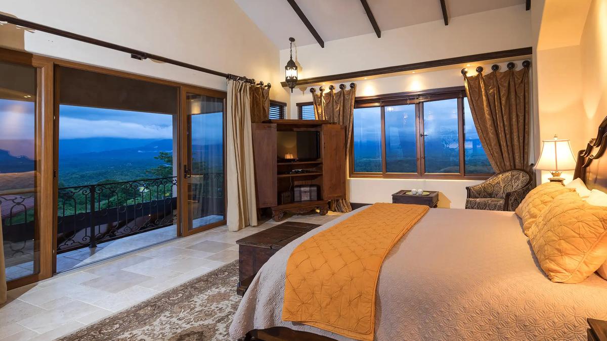 Master bedroom at Villa Marbella with balcony doors and evening valley views
