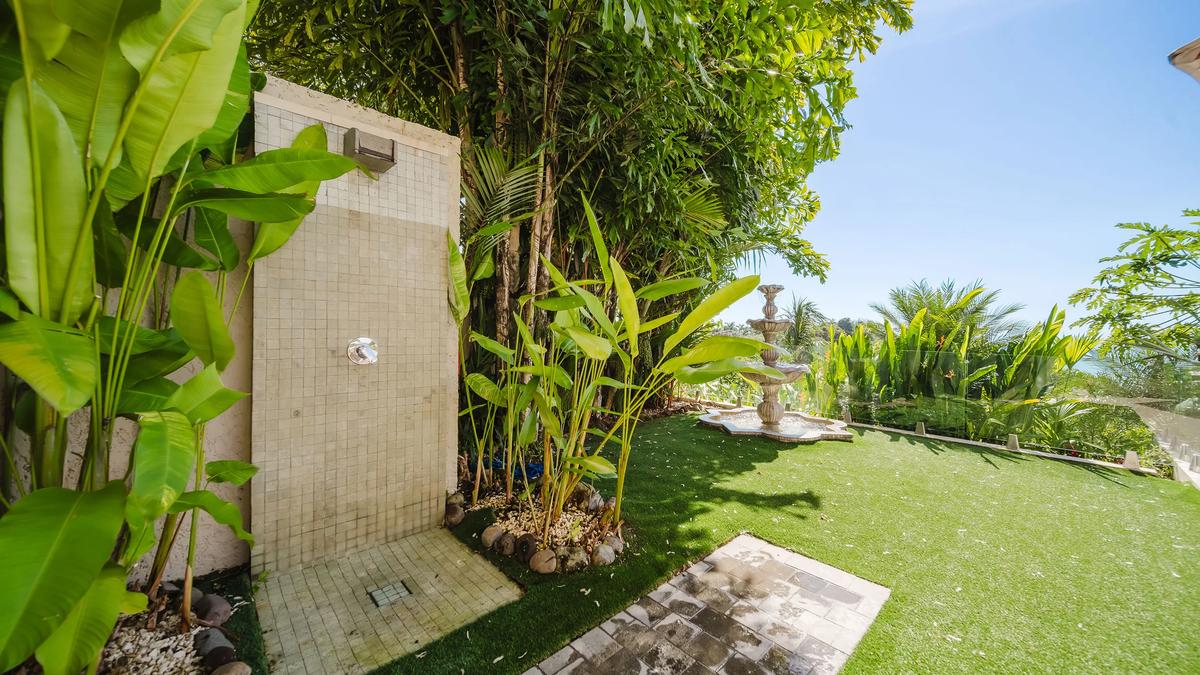 Outdoor rain shower at Casa Nola set in a lawn among heliconias and palms