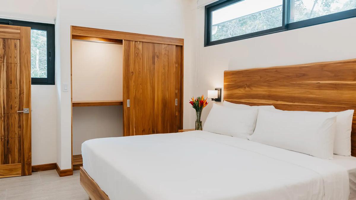 King bed and open teak wardrobe beneath clerestory windows at Casa Dos Cascadas