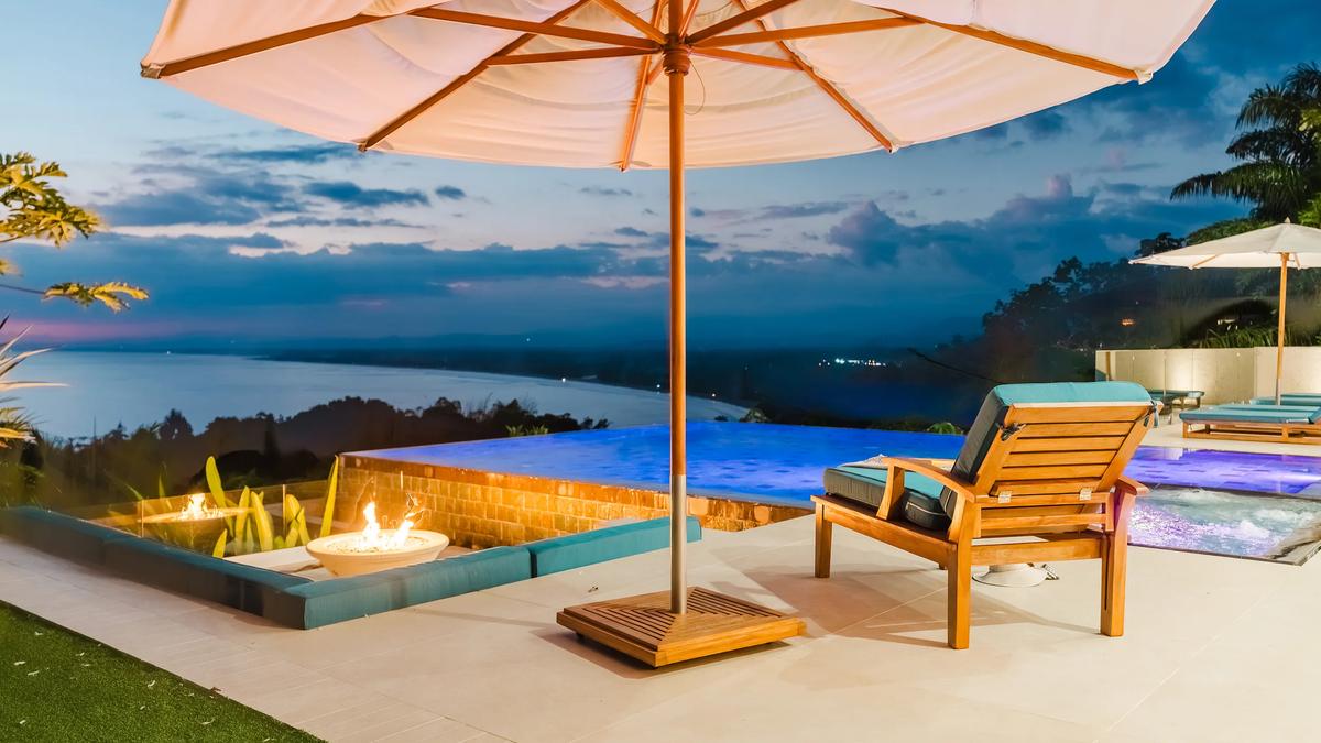 Firepit and umbrella on the Casa Nola terrace at dusk, ocean beyond