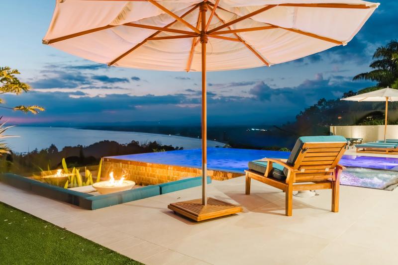 Firepit and umbrella on the Casa Nola terrace at dusk, ocean beyond