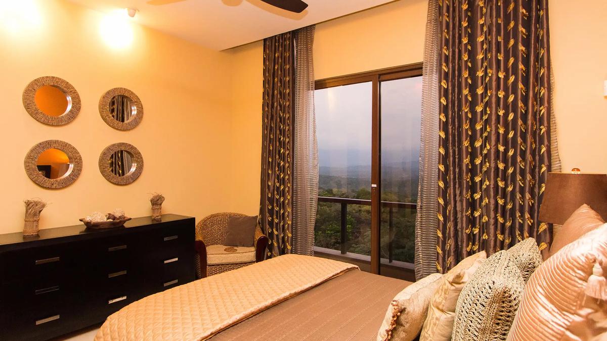 Bedroom at Villa Celaje with gold bedding, round wall mirrors, and a green valley view