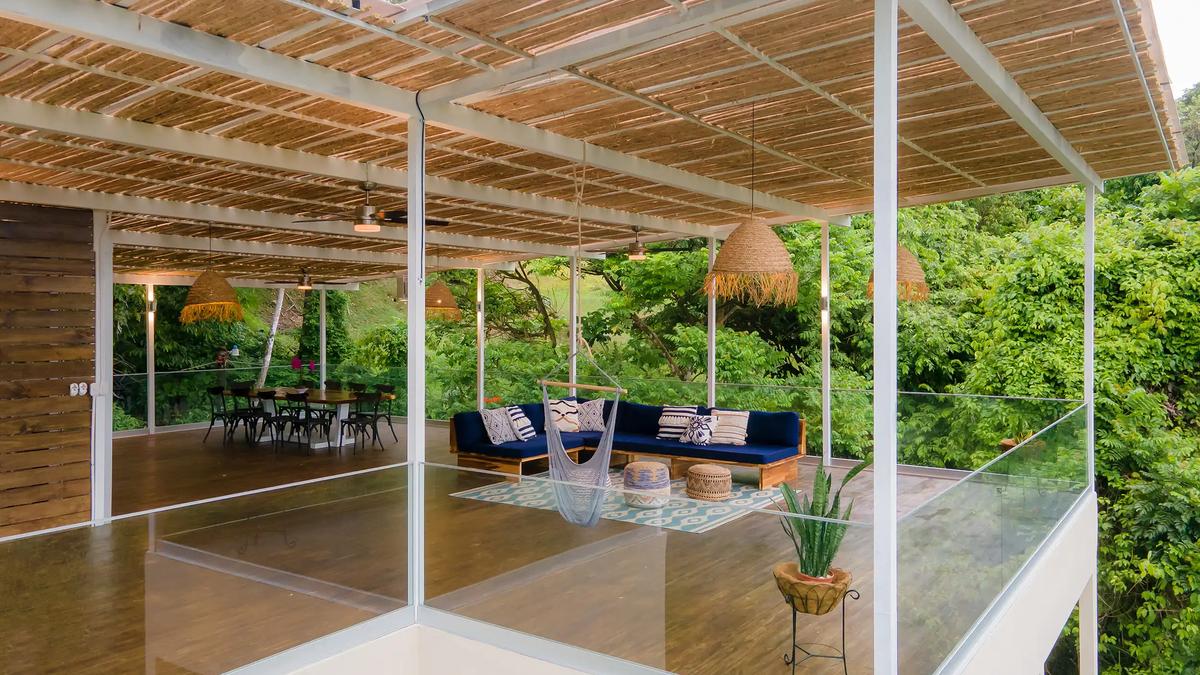 Open-air terrace at Villa Caimito with hanging hammock chair, dining table, and glass railings