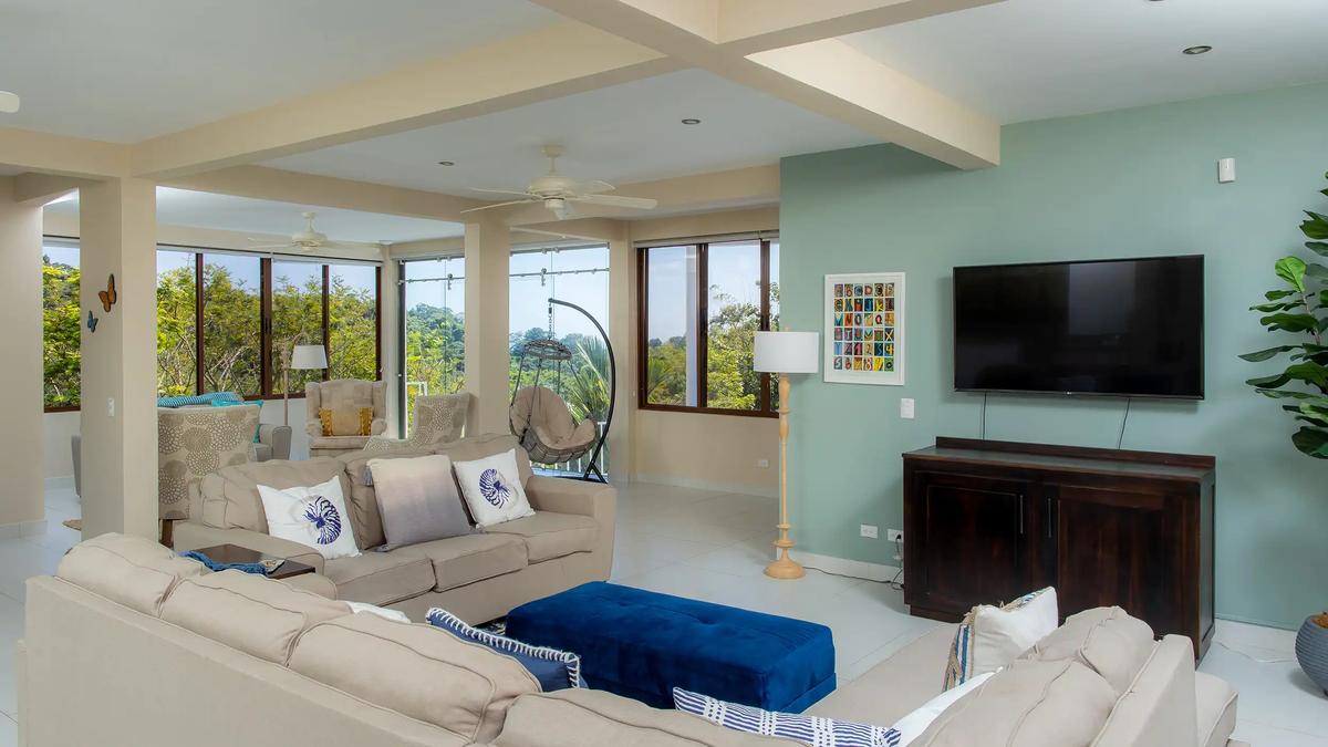 Casa Mariposa lounge with wall mounted TV, hanging chair, and forest views