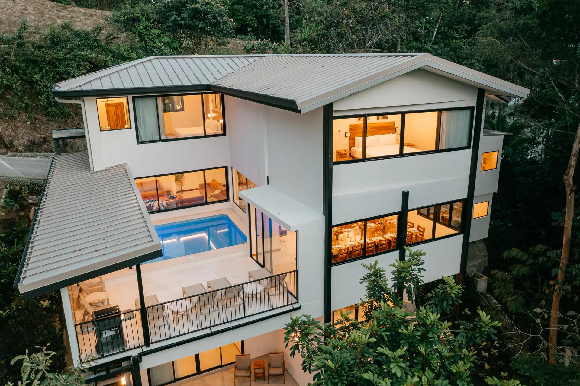 Casa Dos Cascadas at dusk with lit pool deck and rainforest backdrop