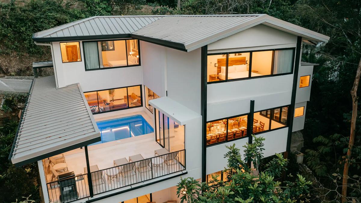 Casa Dos Cascadas at dusk with lit pool deck and rainforest backdrop