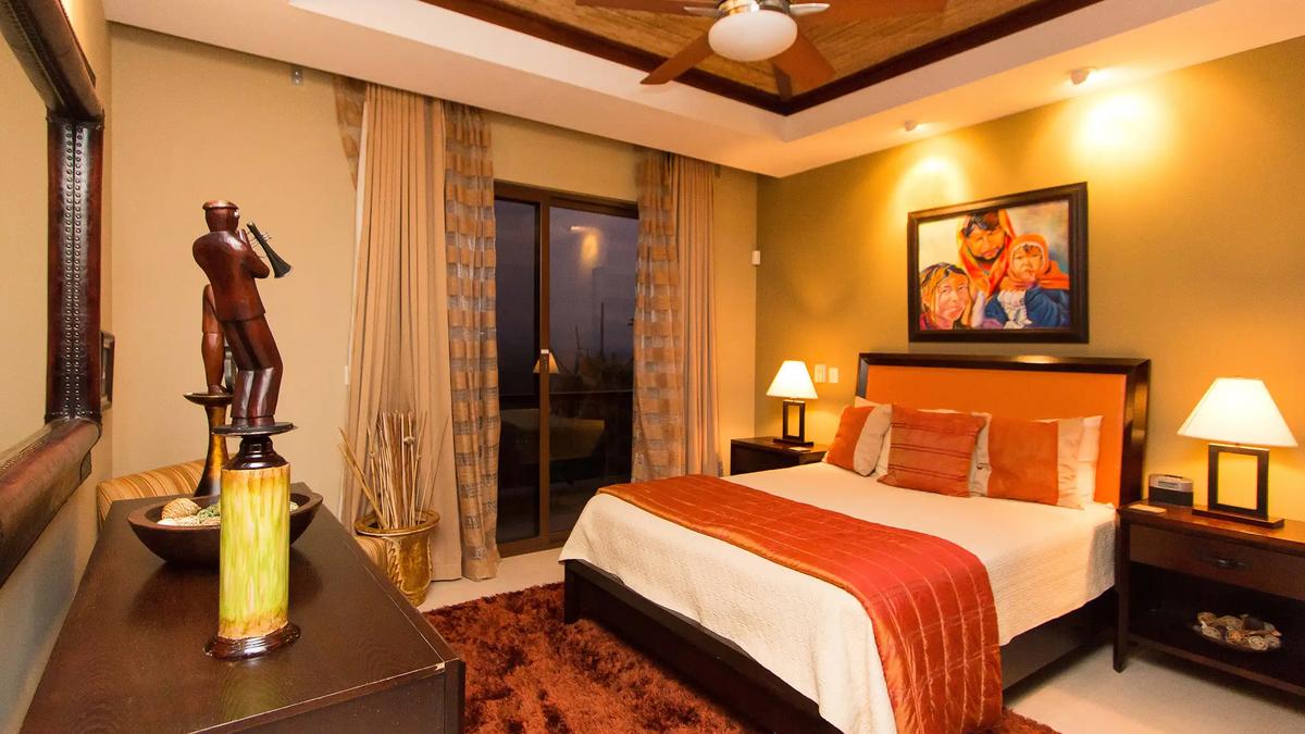 Guest bedroom at Villa Celaje with orange headboard, shag rug, and Costa Rican artwork