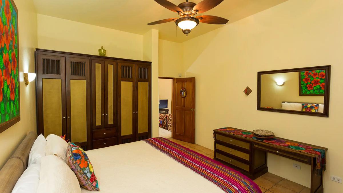 Bedroom at Casa Pura Paz with wood wardrobes, ceiling fan, and embroidered pillow
