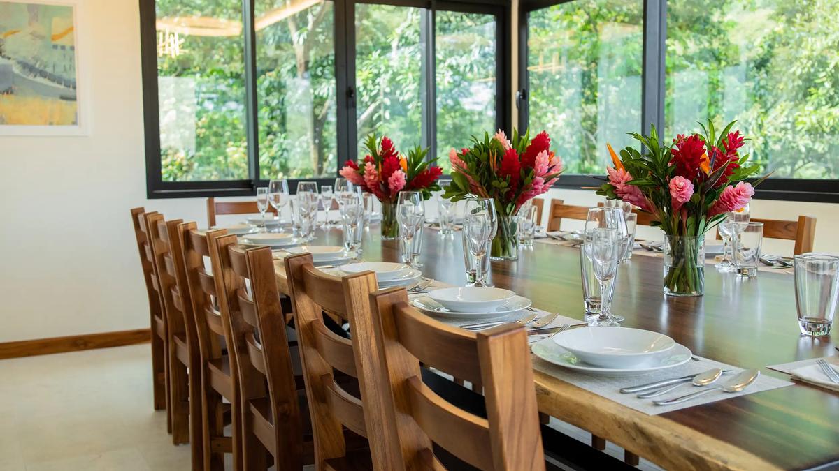 Long dining table at Casa Rambutan set with ginger flower bouquets and jungle views