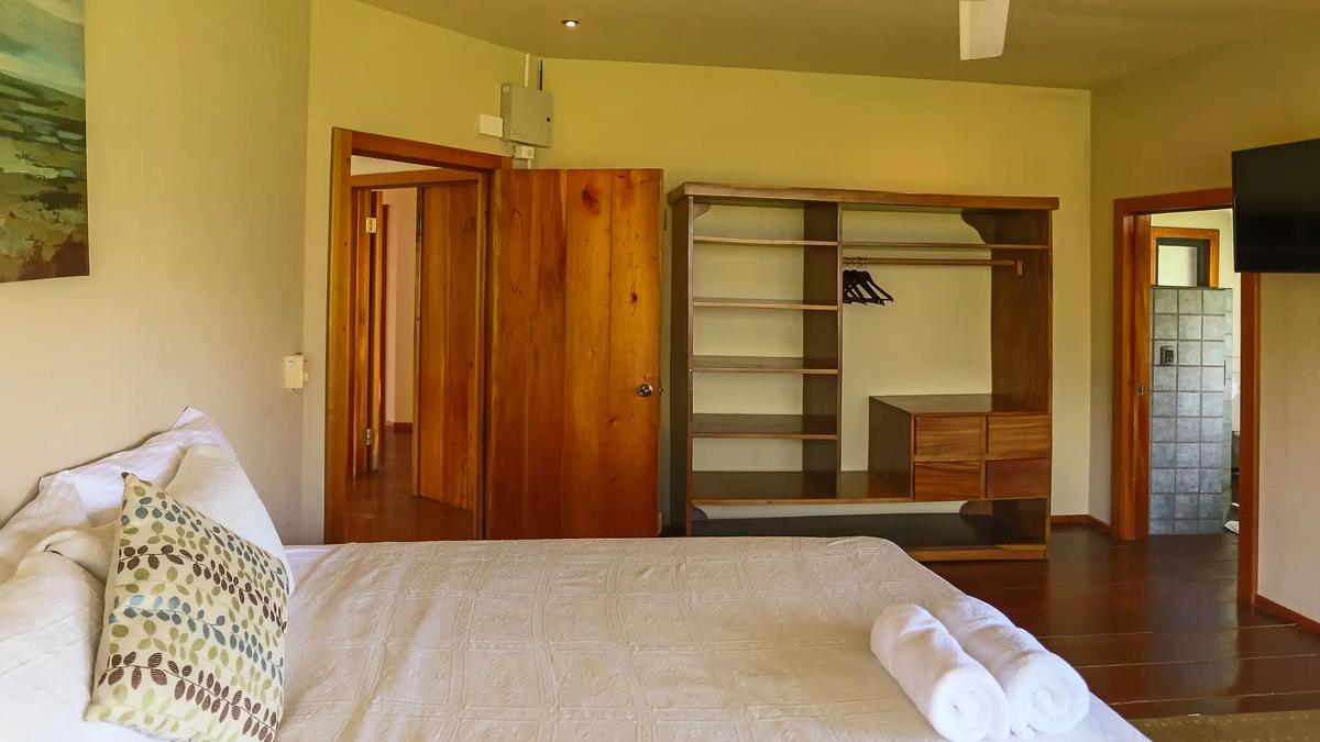 Casa Luz bedroom with rolled towels, open wardrobe shelving and wood doors