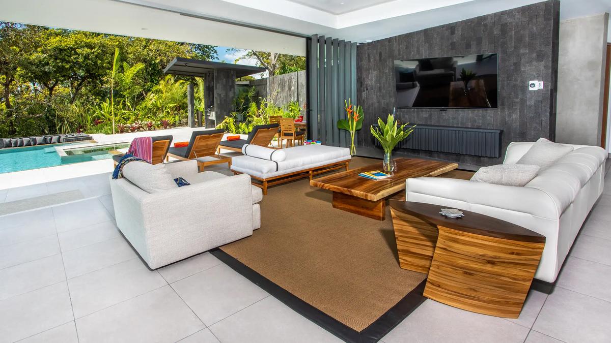 Casa Nueva Vida lounge with lava stone TV wall, wood tables, and poolside loungers
