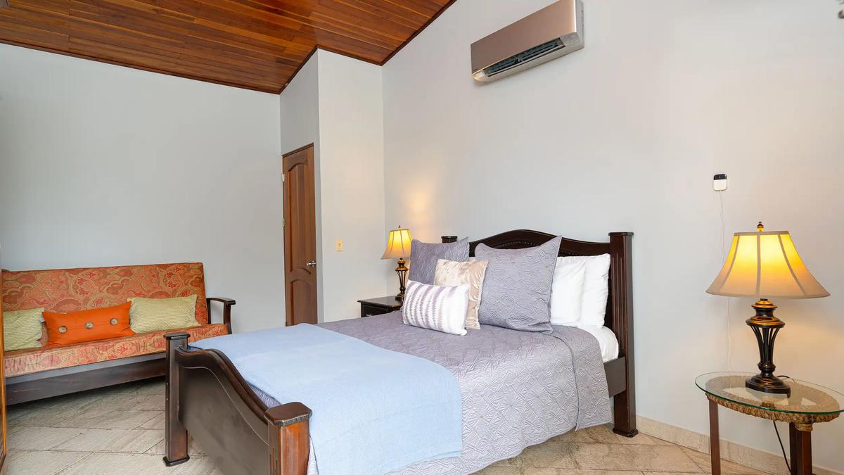 Queen bedroom at Casa Serenidad with dark wood bed frame and patterned futon sofa