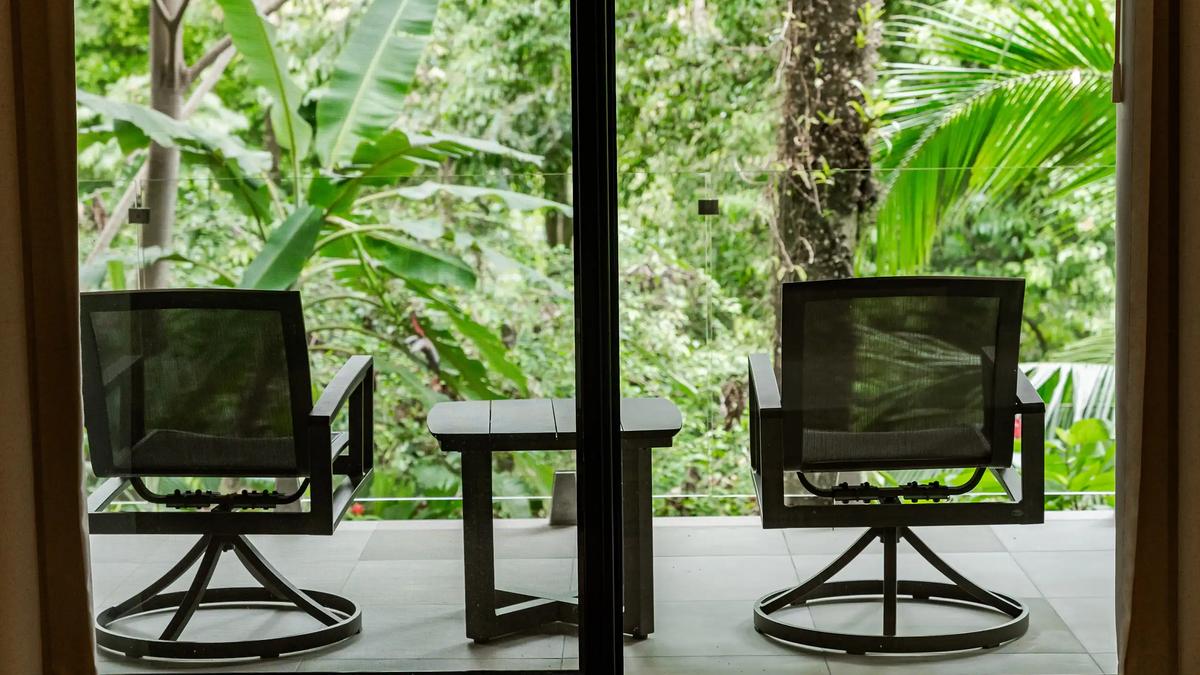 Two swivel chairs on Casa Blue Marlin's patio facing dense jungle greenery