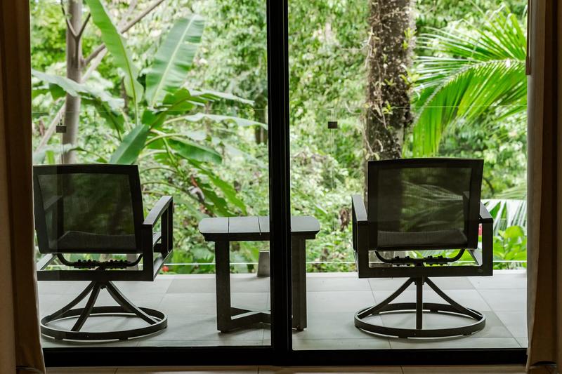 Two swivel chairs on Casa Blue Marlin's patio facing dense jungle greenery