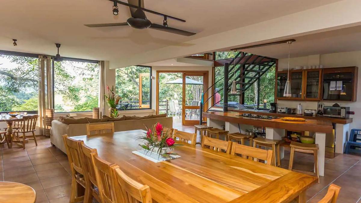 Long teak dining table at Casa Luz with open kitchen and spiral staircase