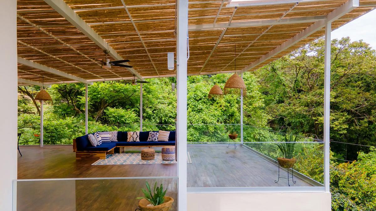 Covered rooftop terrace at Villa Caimito with navy sectional, bamboo ceiling, and jungle canopy views