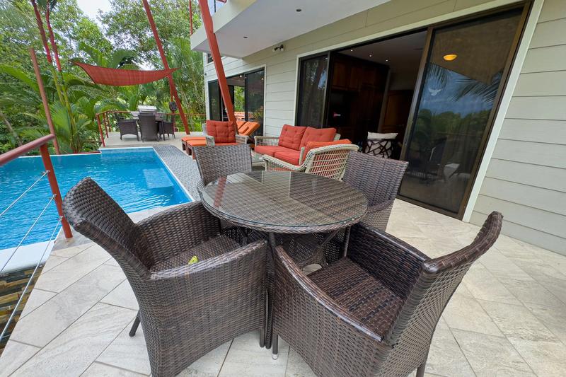 Poolside patio at Casa Serenidad with round wicker table and orange lounge cushions