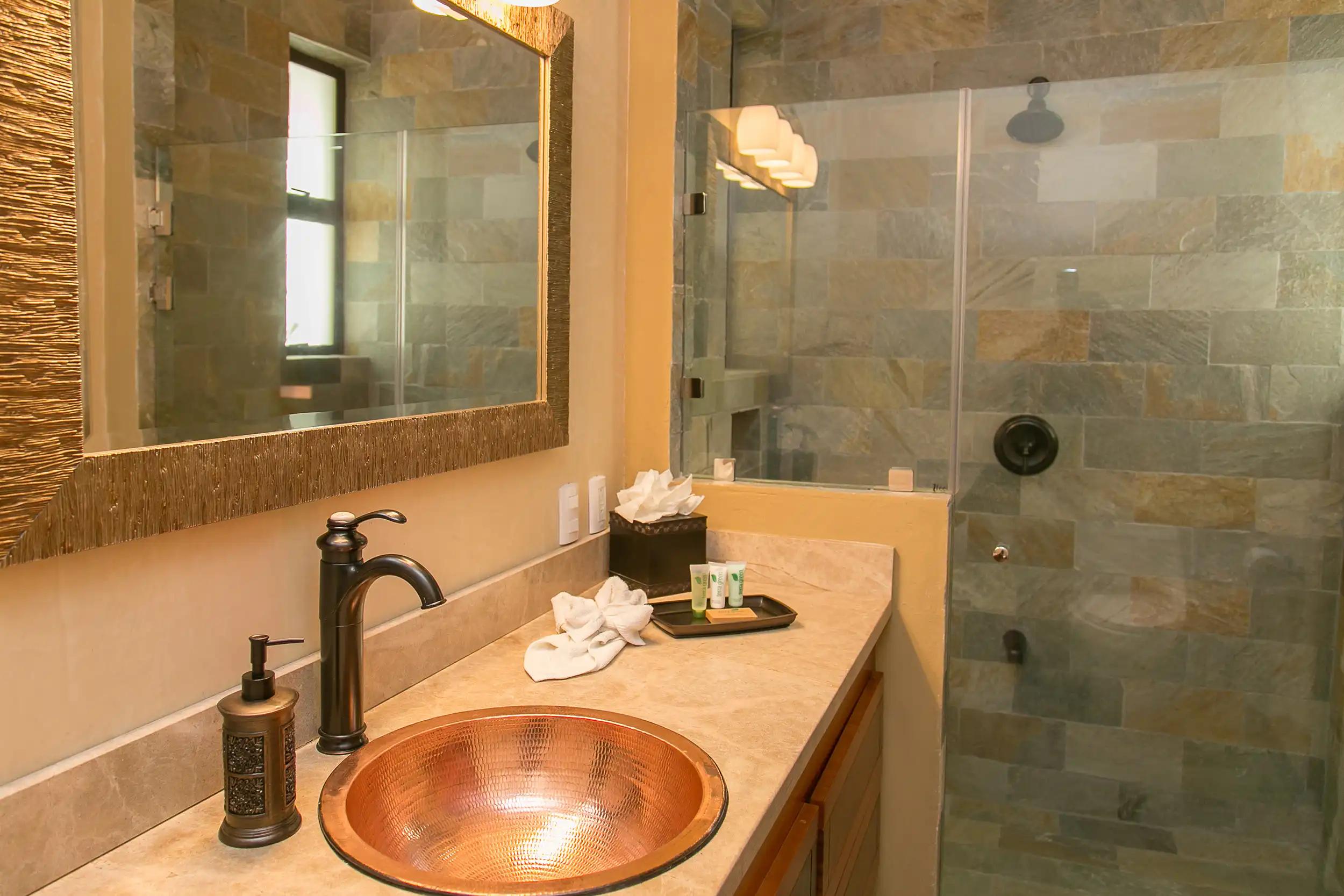 Copper bowl sink and stone-tiled walk-in shower at Casa Anaka