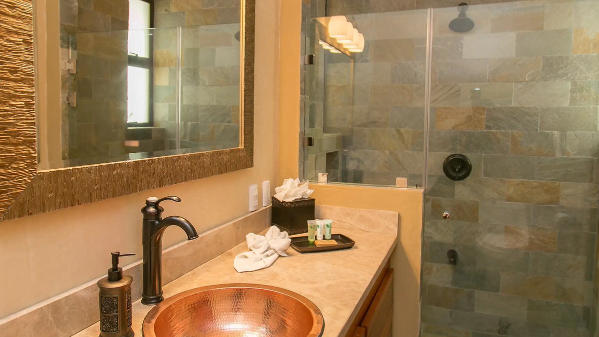Copper bowl sink and stone-tiled walk-in shower at Casa Anaka