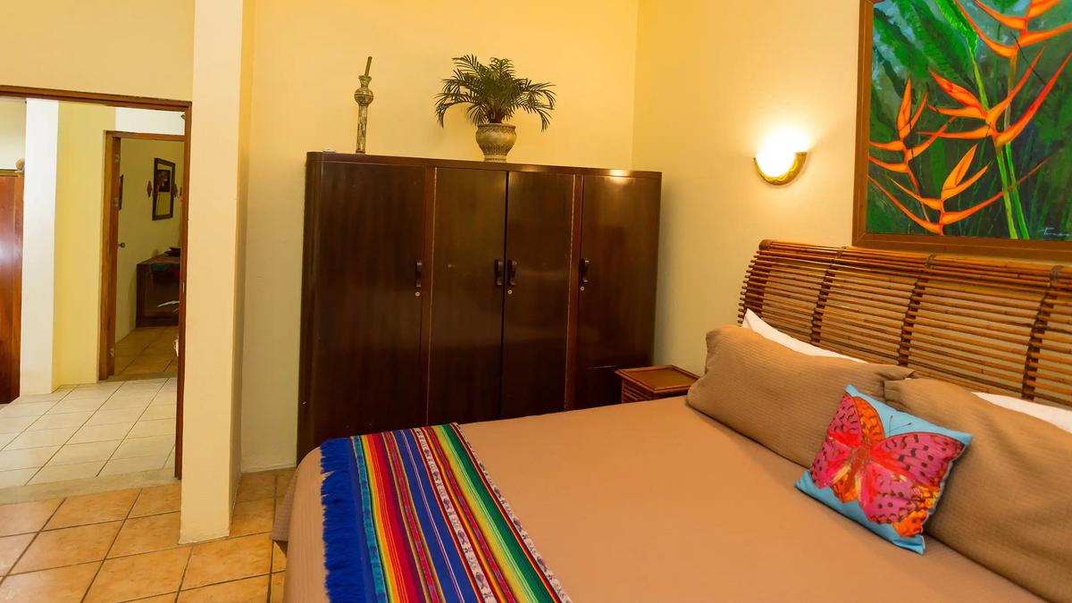 Casa Pura Paz bedroom with bamboo headboard, butterfly pillow, and tropical flower painting