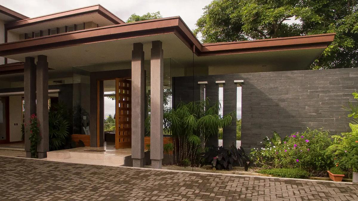 Covered front entrance of Casa Contee with stone wall and tropical plantings