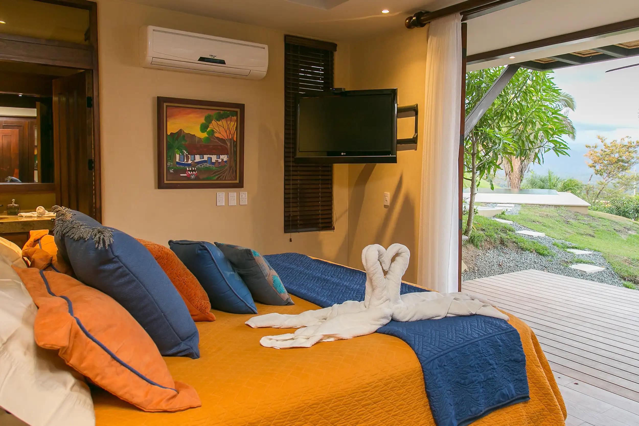 Bedroom with mounted TV opening to the deck and garden at Casa Anaka