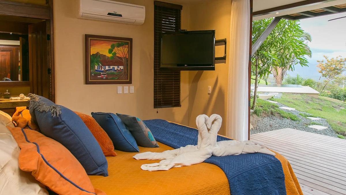 Bedroom with mounted TV opening to the deck and garden at Casa Anaka