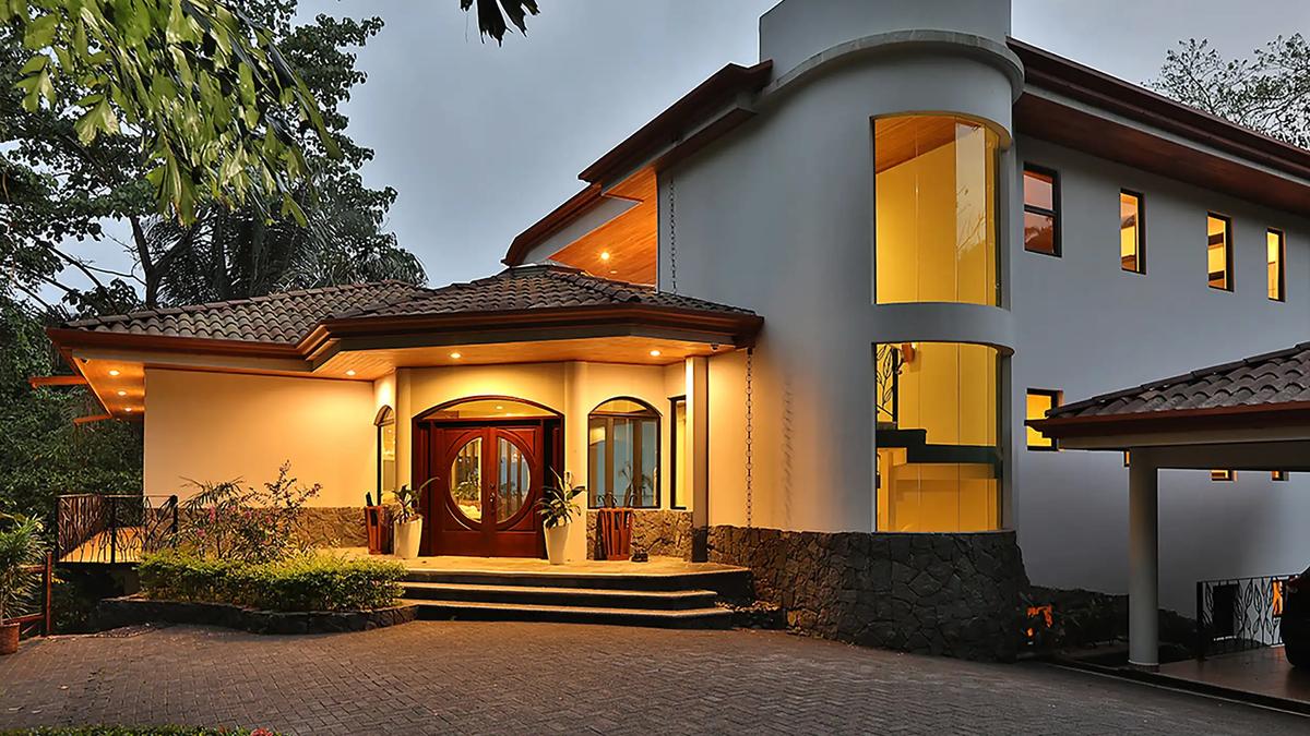 Casa Anjali's arched mahogany entrance and glass stair tower lit at dusk