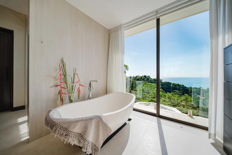 Freestanding bathtub at Casa Nola beside floor to ceiling glass and the ocean