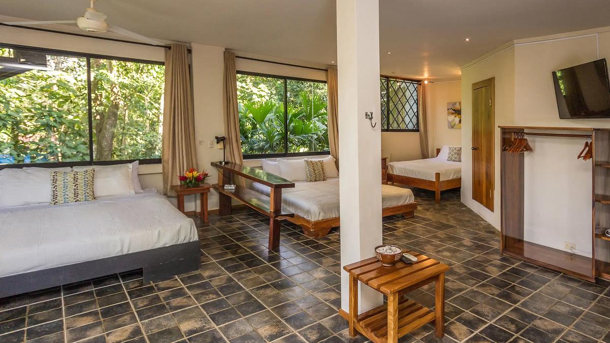 Open plan Casa Luz bedroom with three beds, TV and hanging rack