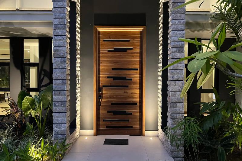 Backlit teak front door between stone columns at Villa de Grace