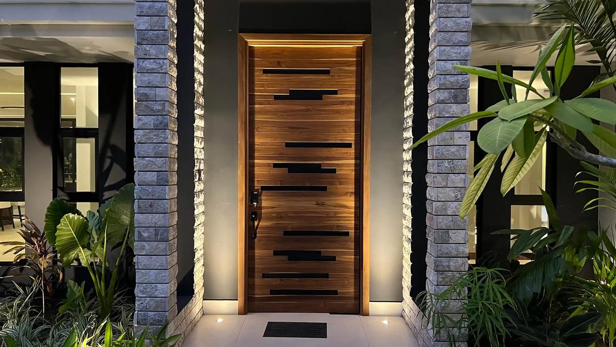 Backlit teak front door between stone columns at Villa de Grace