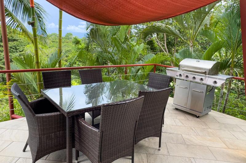 Casa Serenidad deck with wicker dining set and stainless gas grill overlooking jungle
