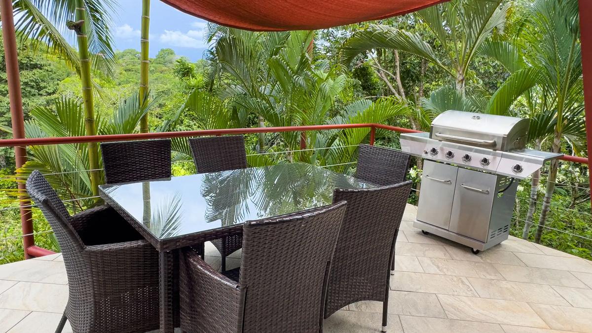 Casa Serenidad deck with wicker dining set and stainless gas grill overlooking jungle