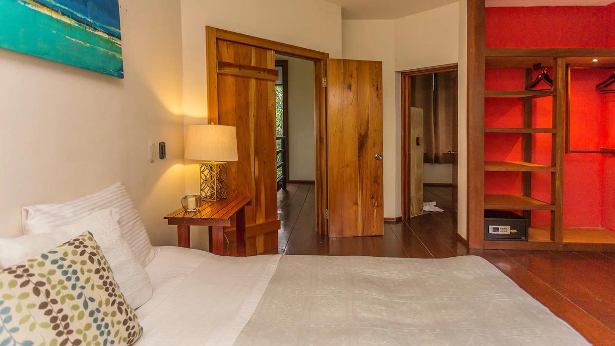 Casa Luz bedroom with teak doors, open closet and turquoise seascape painting