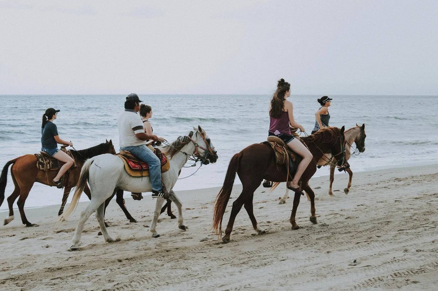 Group riding horses along the beach at low tide, Manuel Antonio