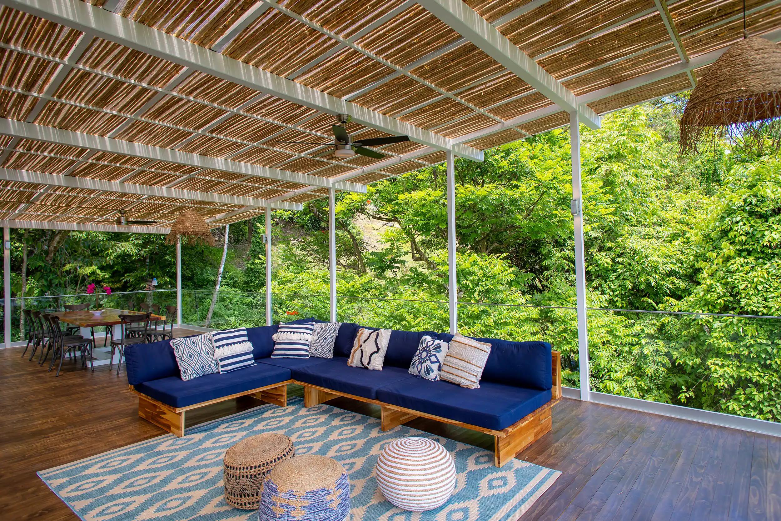 Navy L-shaped sectional at Villa Caimito framed by rainforest greenery beyond glass railings