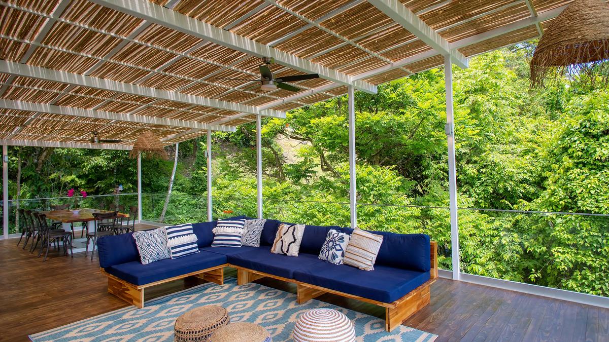 Navy L-shaped sectional at Villa Caimito framed by rainforest greenery beyond glass railings