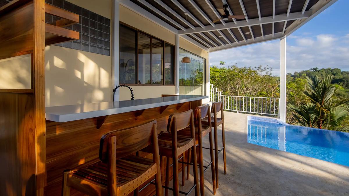 Poolside bar with wooden stools beside the infinity pool at Casa Mariposa