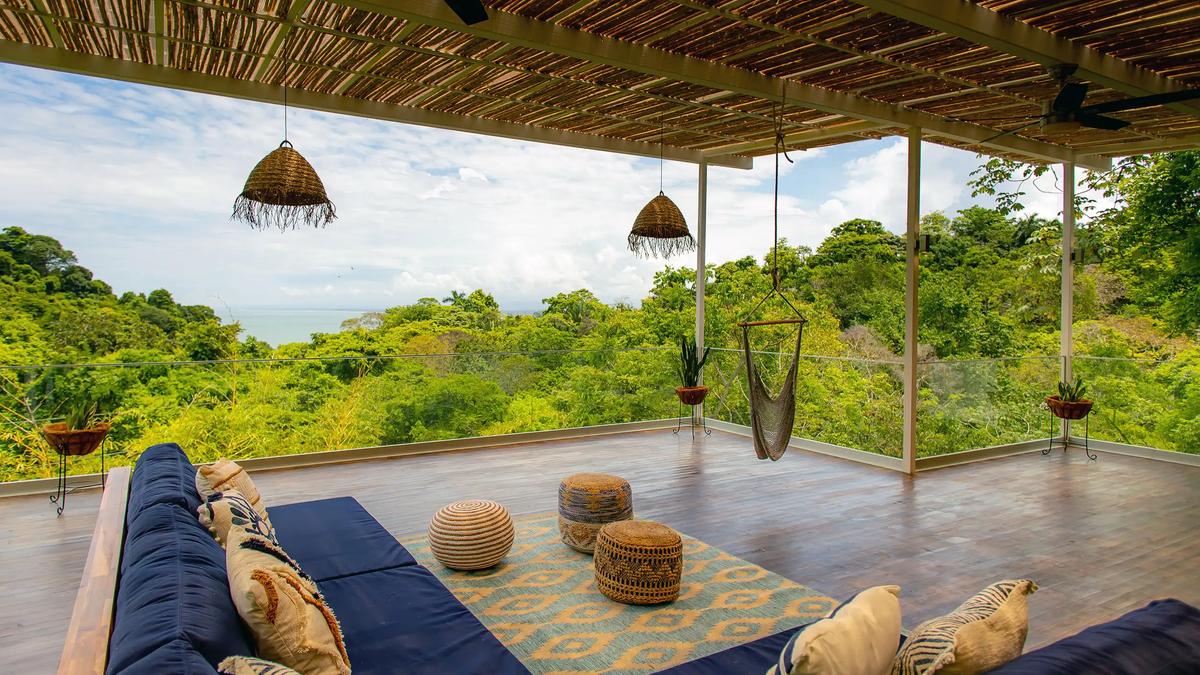 Villa Caimito's terrace lounge with poufs, hammock chair, and sweeping jungle and sea views