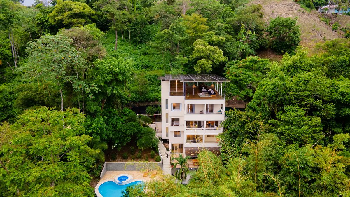 Four-story Villa Caimito rising from the rainforest hillside above its curved pool and jacuzzi