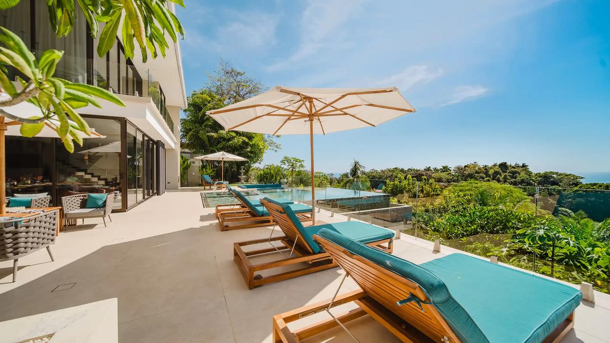 Sun loungers line the glass railed terrace at Casa Nola beside the infinity pool