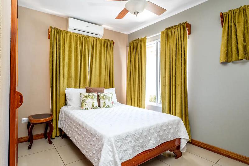Guest bedroom with queen bed, ceiling fan, and green curtains at Casa Alta Vista
