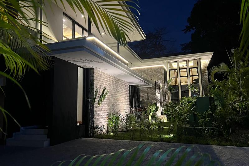 Palms frame the stone walls and lit eaves of Villa de Grace at night