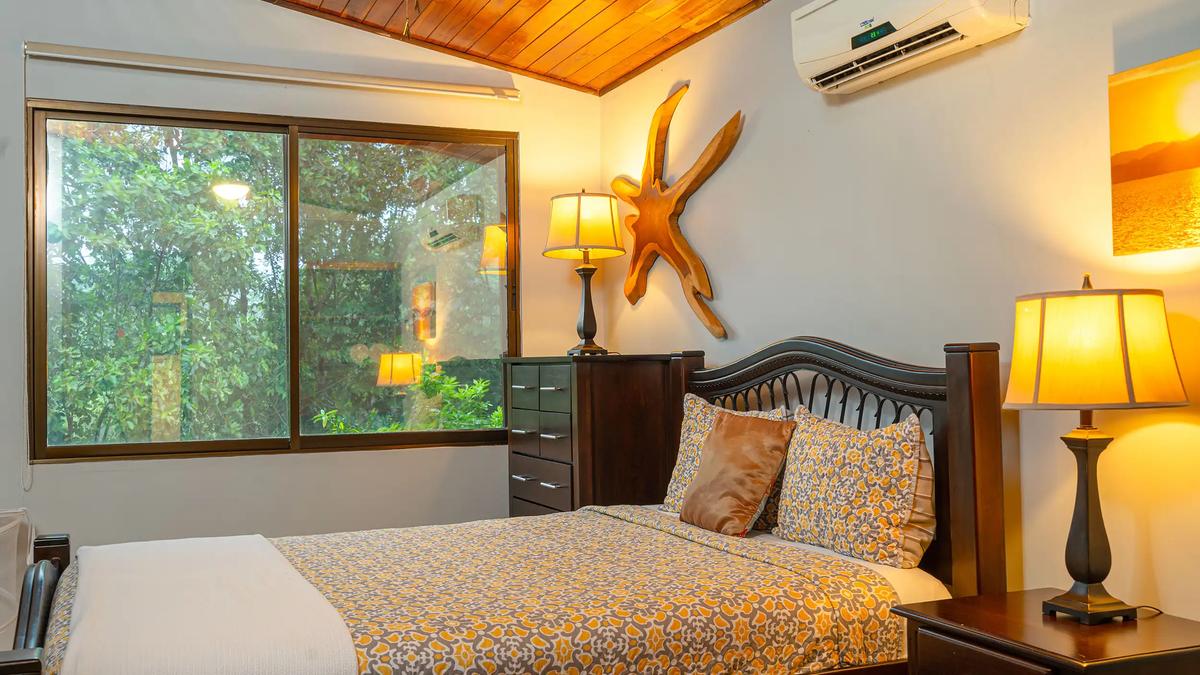 Warm lit Casa Serenidad bedroom with yellow floral bedding and carved driftwood wall art
