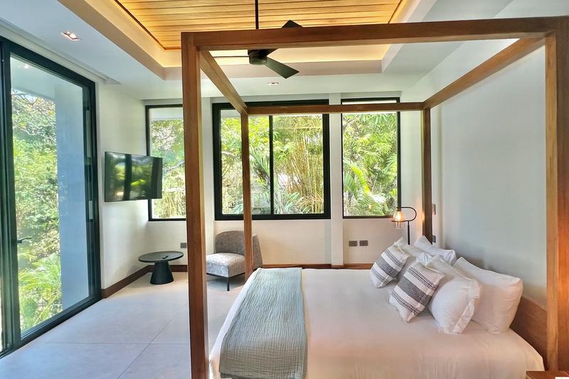 Villa de Grace bedroom with canopy bed, wall TV, and floor to ceiling glass