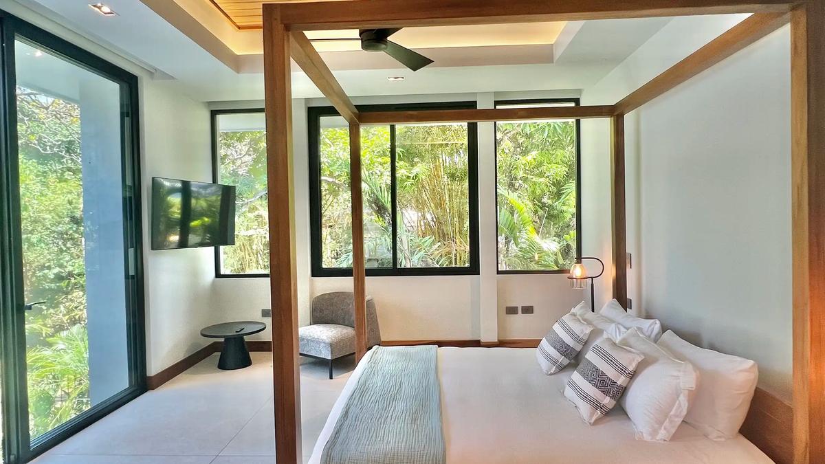 Villa de Grace bedroom with canopy bed, wall TV, and floor to ceiling glass