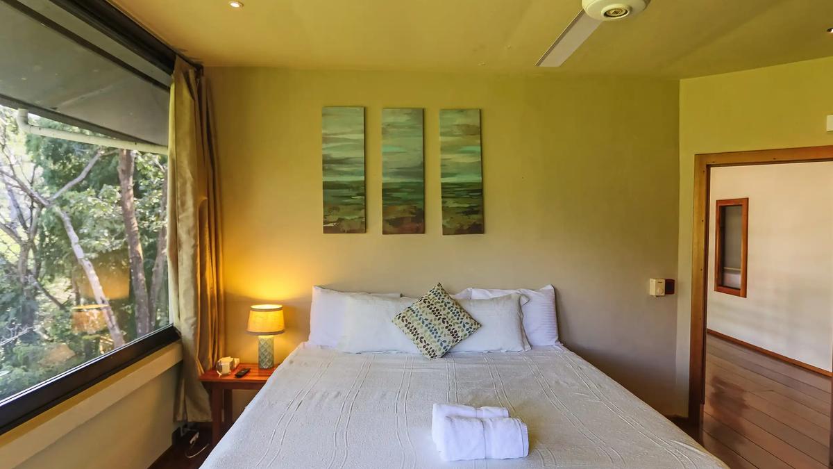 King bed at Casa Luz beneath a triptych of green seascape paintings